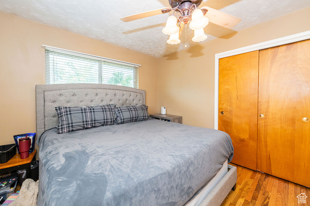 Bedroom with wood finished floors, a closet, ceiling fan, and a textured ceiling