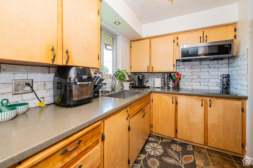 Kitchen with stainless steel microwave, tasteful backsplash, and black electric stovetop