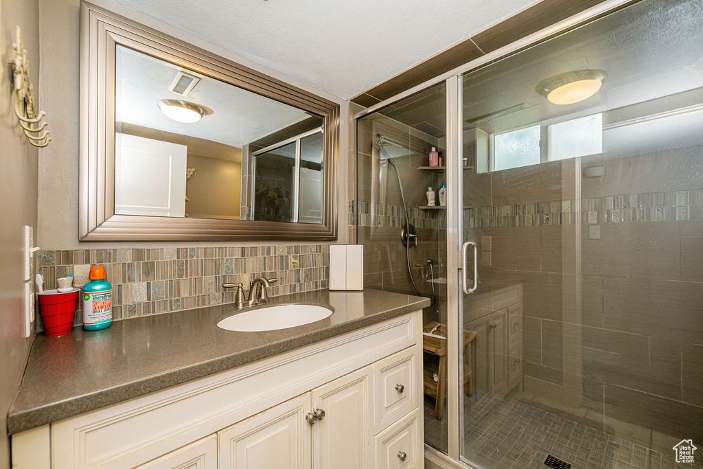 Bathroom with vanity, a shower stall, and backsplash