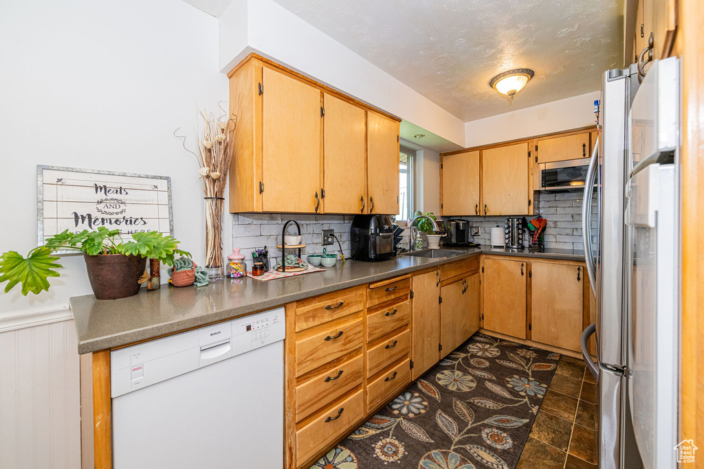 Kitchen with stainless steel appliances, tasteful backsplash, and a wainscoted wall