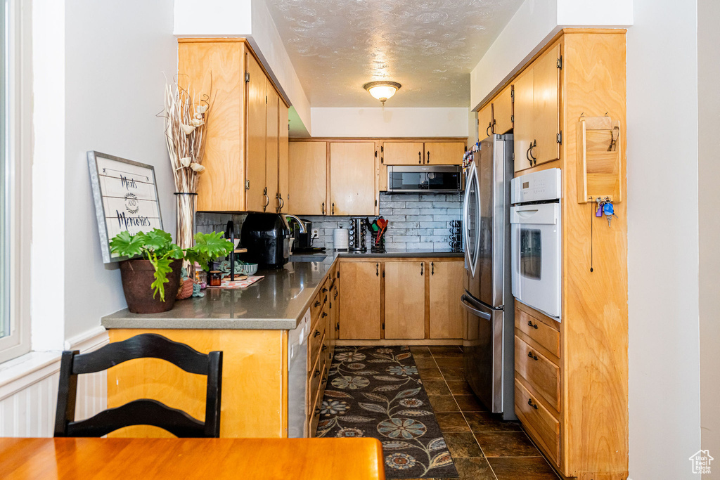 Kitchen with appliances with stainless steel finishes, tasteful backsplash, and a textured ceiling