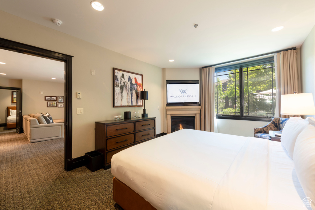 Bedroom with a glass covered fireplace, recessed lighting, and carpet floors