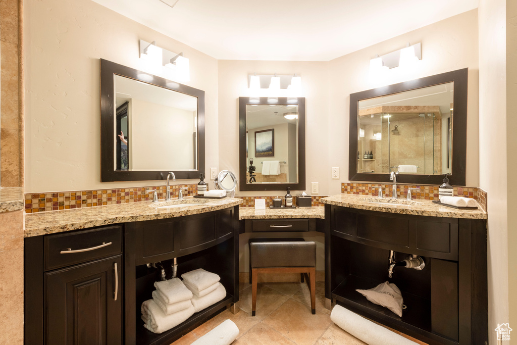 Bathroom featuring a shower stall, tile patterned floors, vanity, and tasteful backsplash