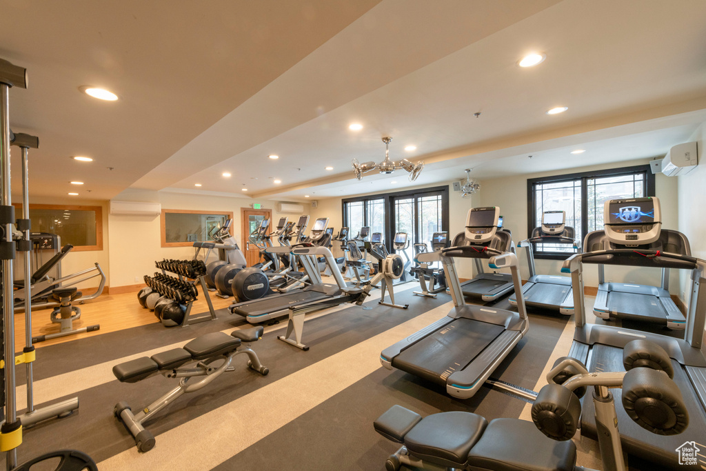 Gym with recessed lighting, a wall unit AC, an AC wall unit, a chandelier, and a raised ceiling