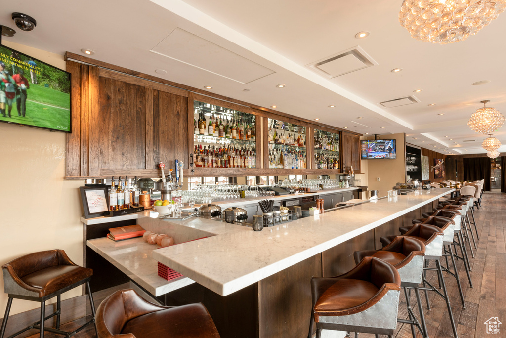 Indoor wet bar with hardwood / wood-style flooring, recessed lighting, and a chandelier