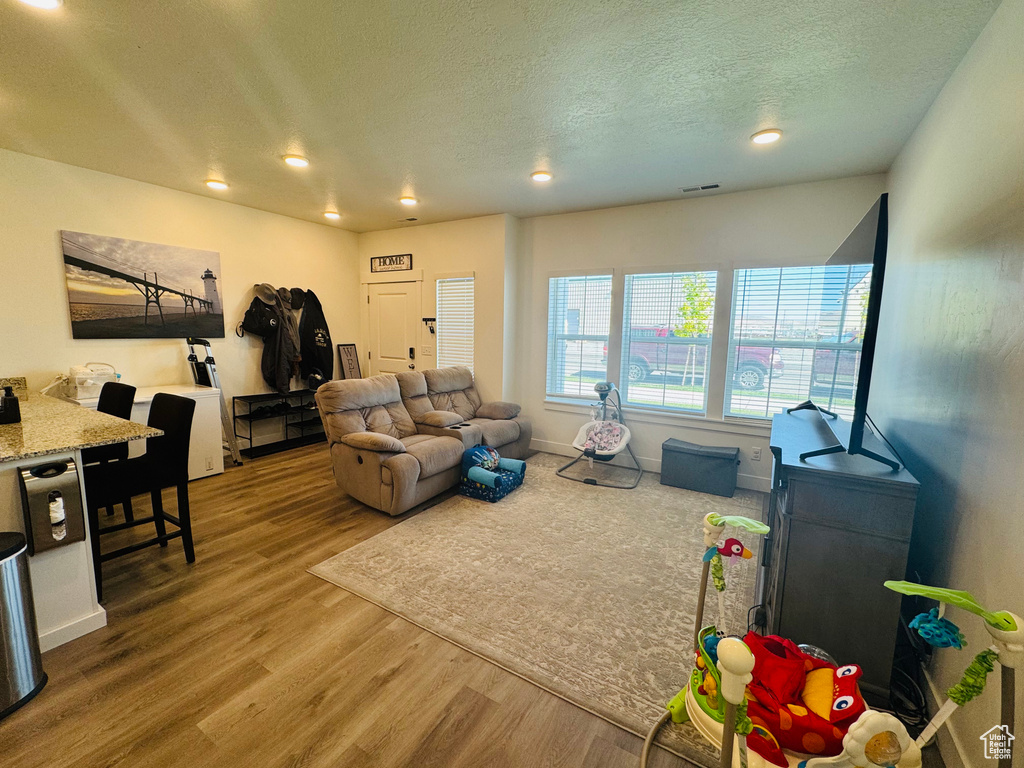 Living room with wood finished floors, a textured ceiling, and recessed lighting