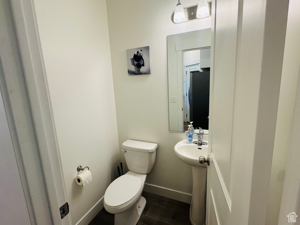 Half bath with toilet and wood finished floors