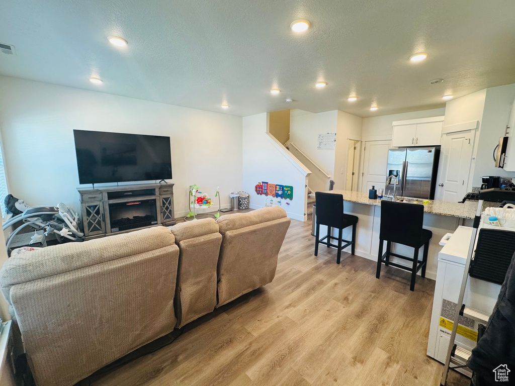 Living room featuring light wood-type flooring, recessed lighting, and stairway
