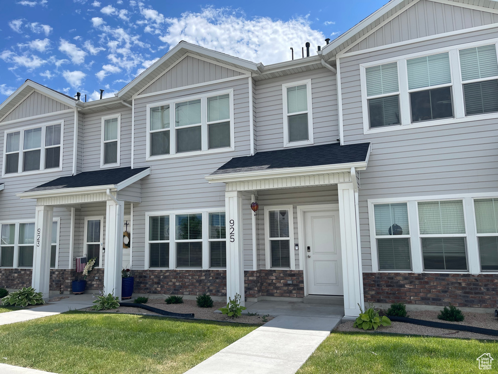 View of property featuring stone siding and a front lawn