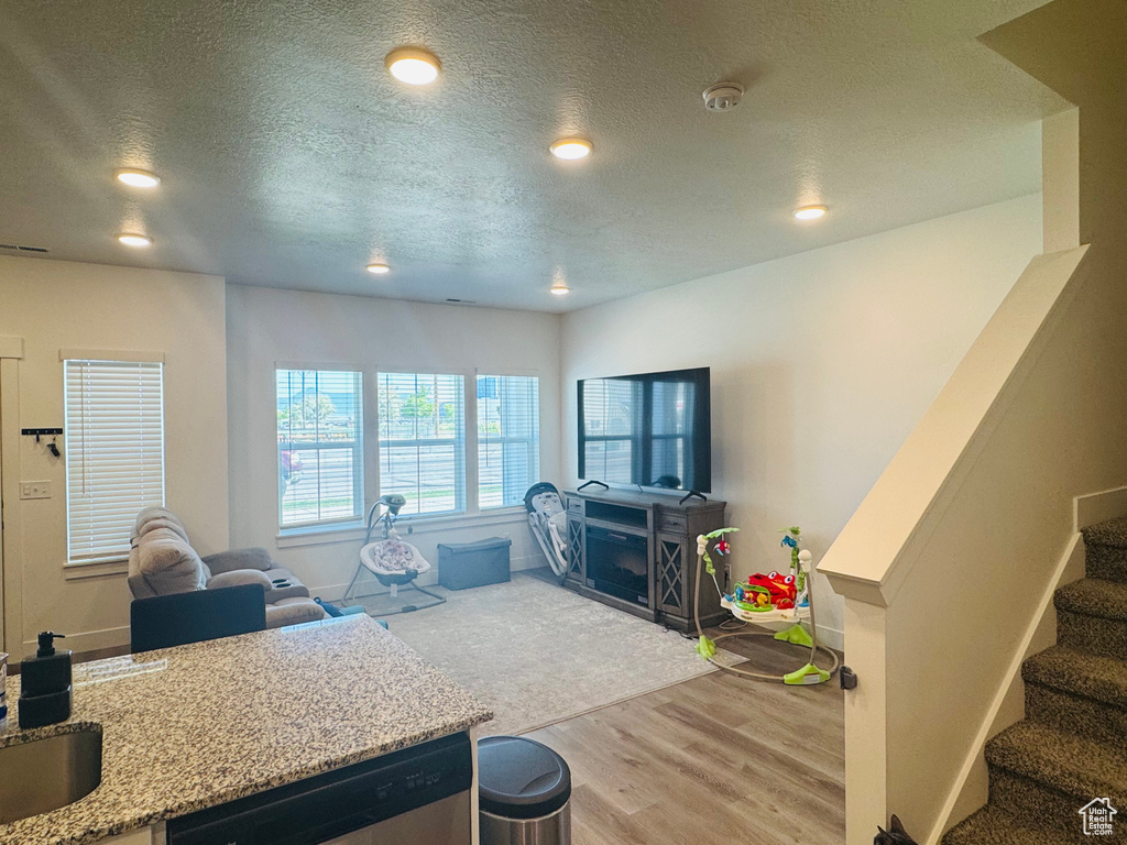 Living area featuring wood finished floors, a textured ceiling, recessed lighting, and stairway