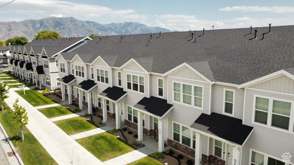 View of front of property with board and batten siding, stone siding, a mountain view, and roof with shingles
