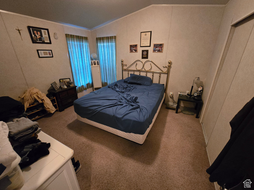 Bedroom with vaulted ceiling, carpet, and crown molding