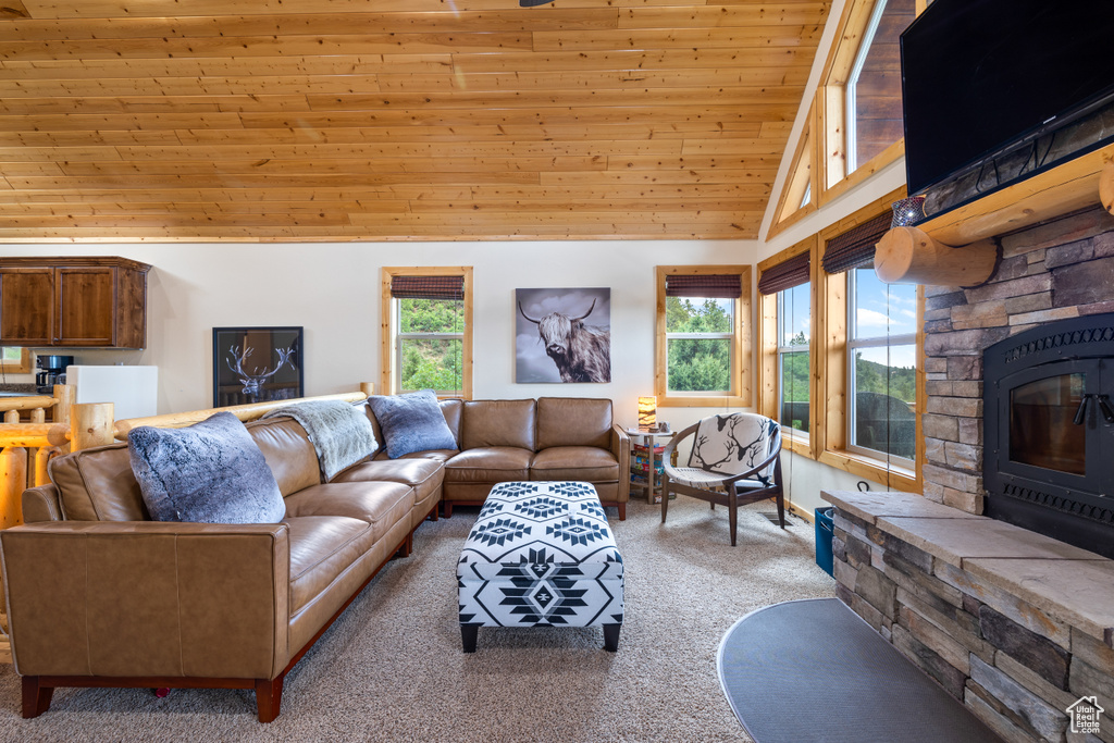 Living area featuring carpet floors, healthy amount of natural light, wooden ceiling, high vaulted ceiling, and a stone fireplace