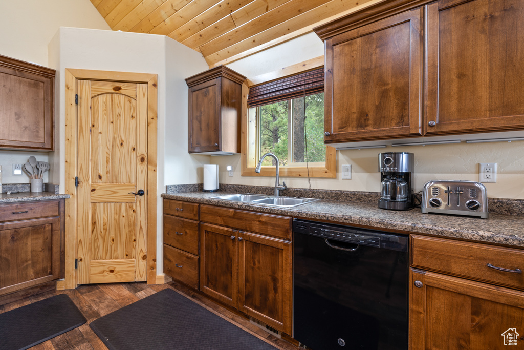 Kitchen with dishwasher, dark countertops, dark wood-type flooring, and lofted ceiling