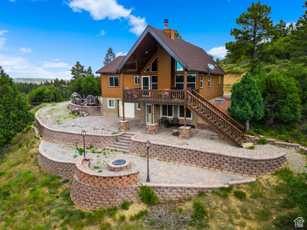 Rear view of house featuring an outdoor fire pit, a patio area, a wooden deck, stairway, and a chimney