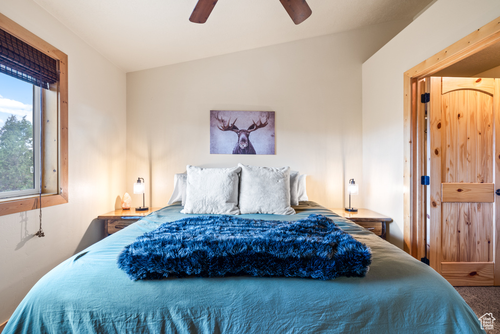 Bedroom with vaulted ceiling, a ceiling fan, and carpet flooring