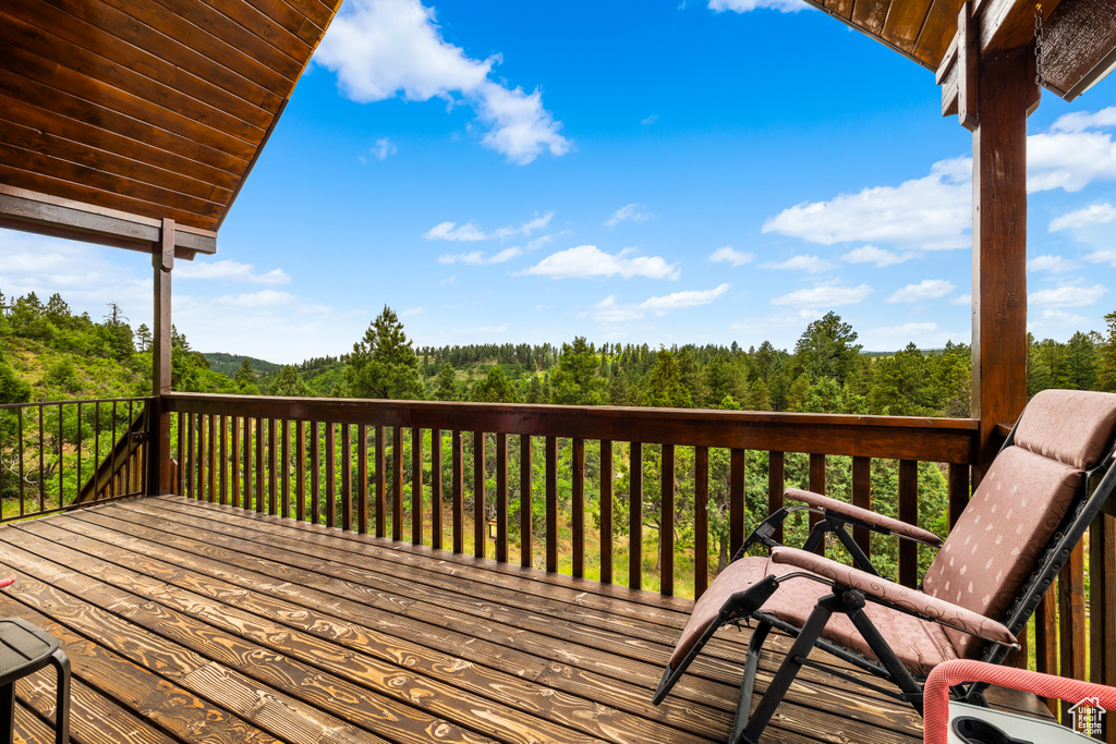 Wooden terrace featuring a wooded view