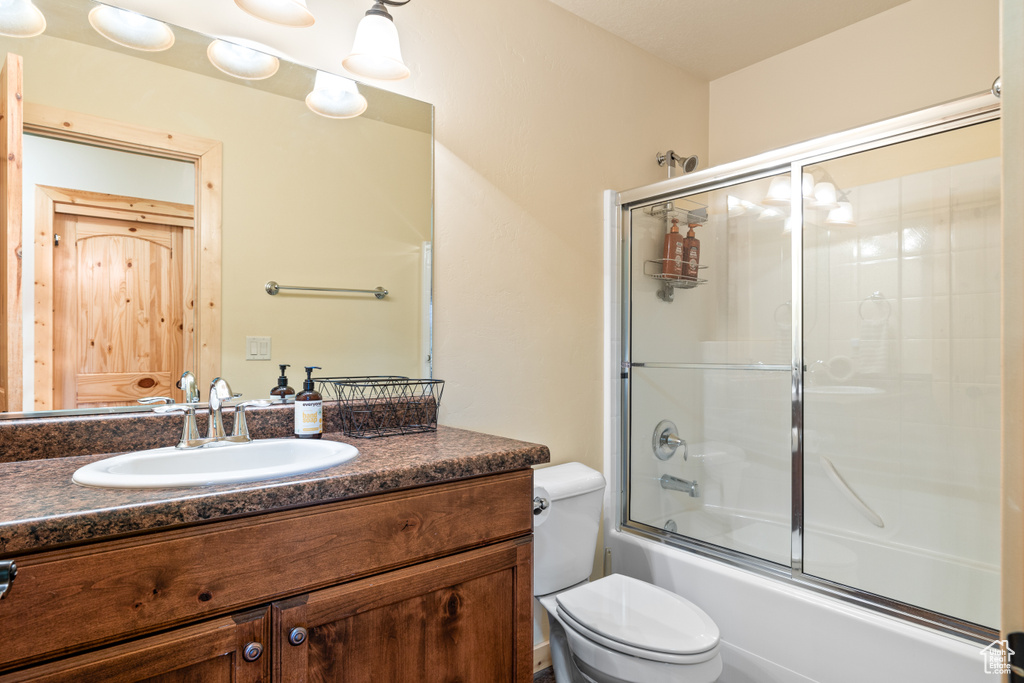 Bathroom featuring vanity and shower / bath combination with glass door