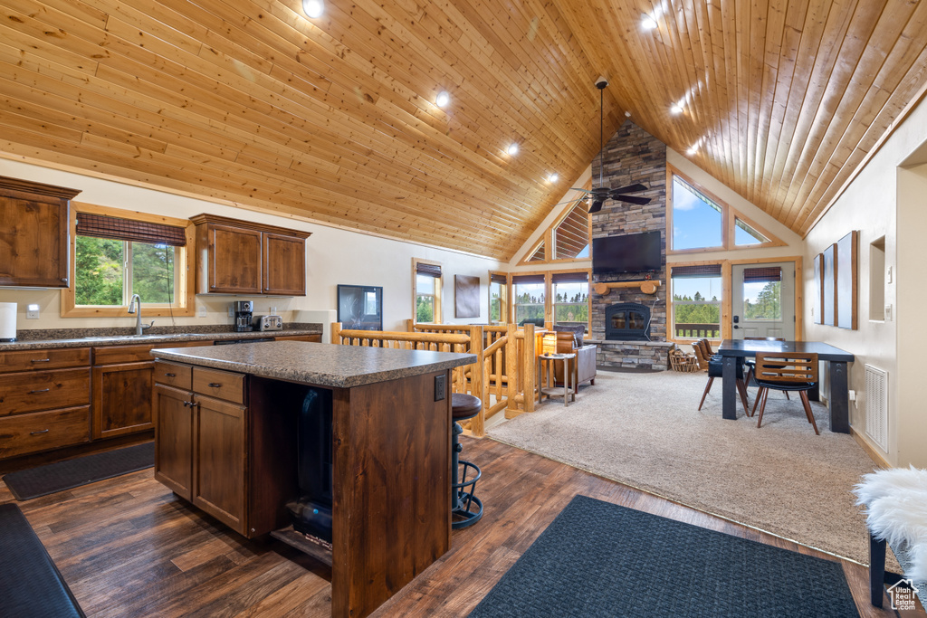 Kitchen featuring high vaulted ceiling, a stone fireplace, a center island, a ceiling fan, and open floor plan