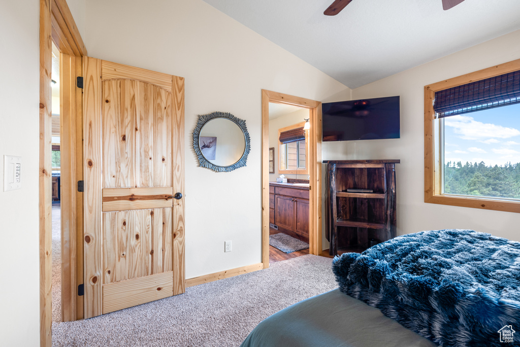 Bedroom featuring lofted ceiling, carpet flooring, connected bathroom, and a ceiling fan