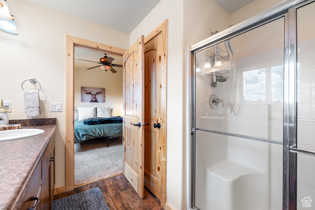 Ensuite bathroom featuring wood finished floors, a stall shower, vanity, and a ceiling fan