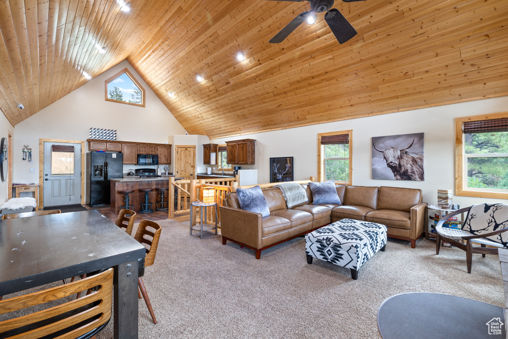 Living area with light carpet, high vaulted ceiling, a ceiling fan, and wood ceiling