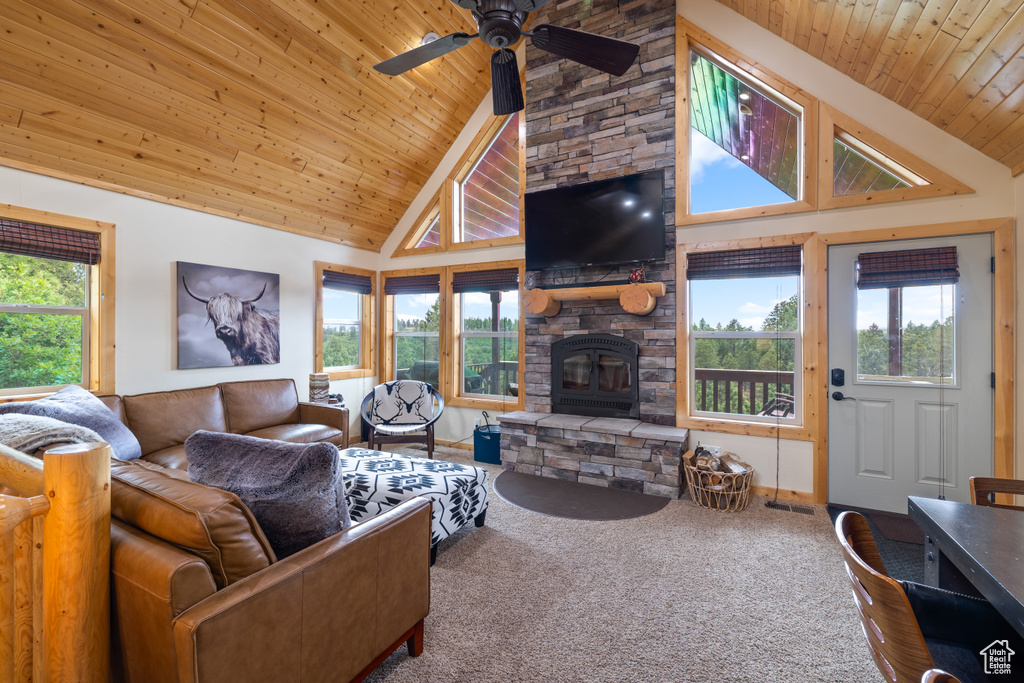 Carpeted living area featuring high vaulted ceiling, ceiling fan, wood ceiling, and a fireplace