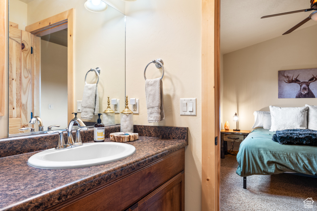 Bathroom with a ceiling fan, vanity, connected bathroom, and lofted ceiling