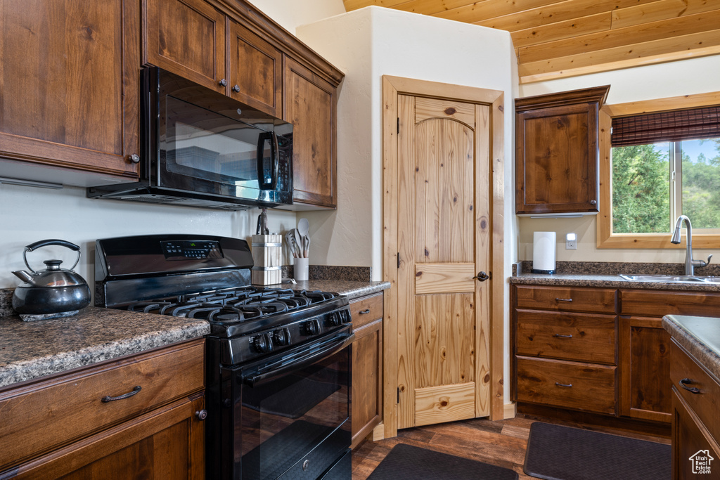 Kitchen featuring black appliances, dark countertops, and dark wood-type flooring