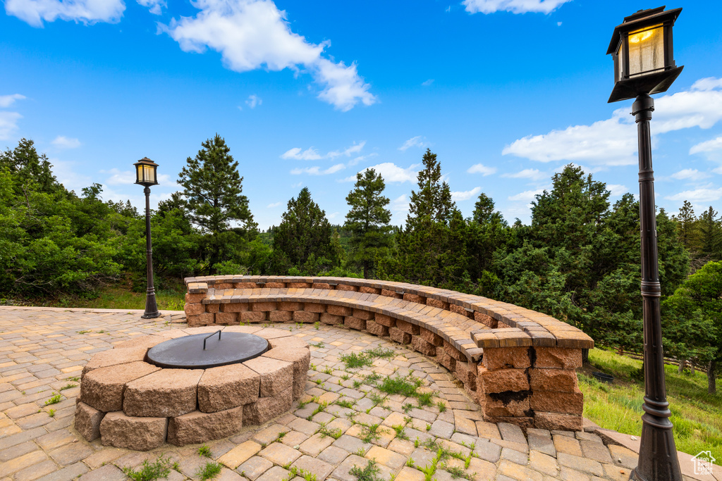 View of patio / terrace featuring an outdoor fire pit and a view of trees