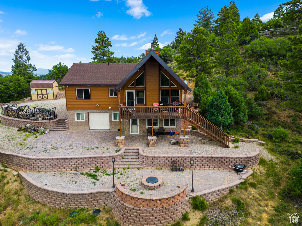 Back of property with stairway, a patio area, an outdoor fire pit, a garage, and a deck