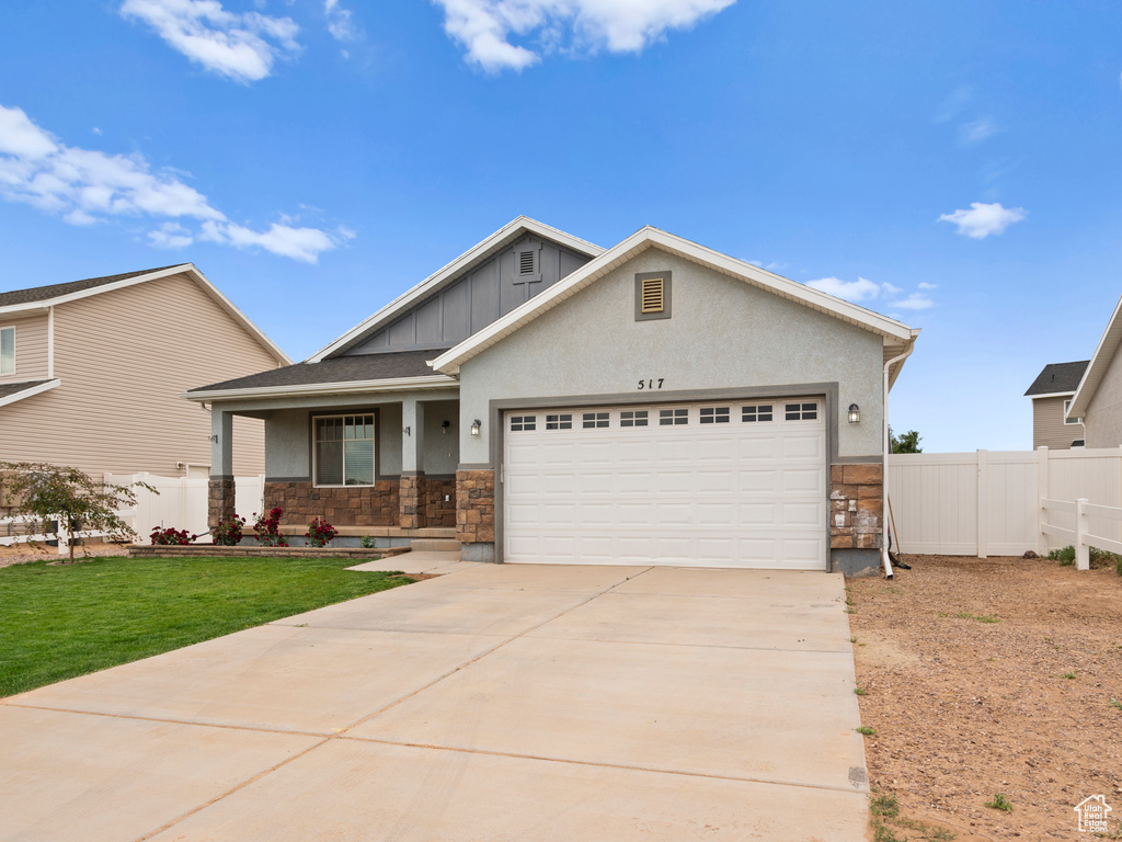 Craftsman inspired home featuring stone siding, an attached garage, board and batten siding, a porch, and driveway