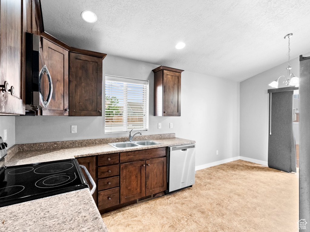 Kitchen with stainless steel appliances, a textured ceiling, dark brown cabinetry, light countertops, and decorative light fixtures