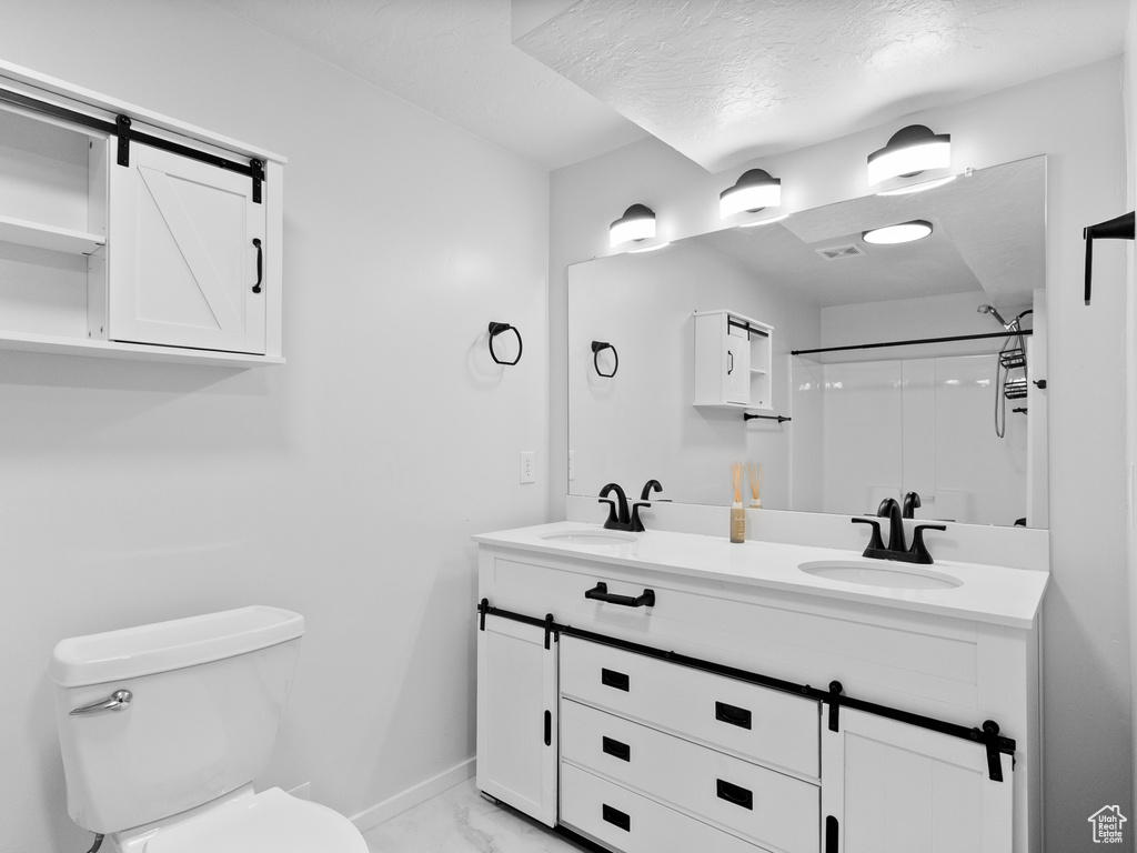 Bathroom featuring double vanity, marble look tiles, and a shower