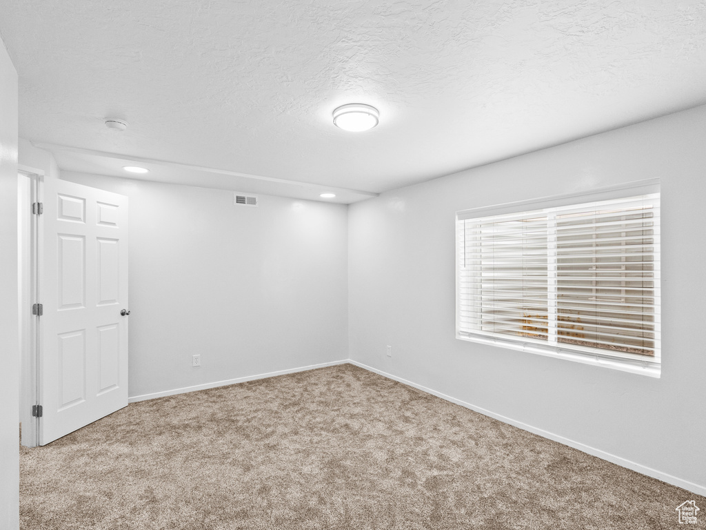 Empty room with carpet flooring, recessed lighting, and a textured ceiling