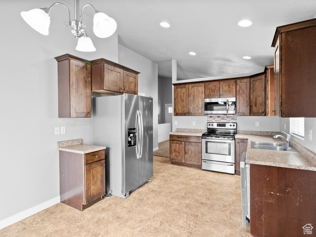 Kitchen with stainless steel appliances, light countertops, recessed lighting, a chandelier, and decorative light fixtures