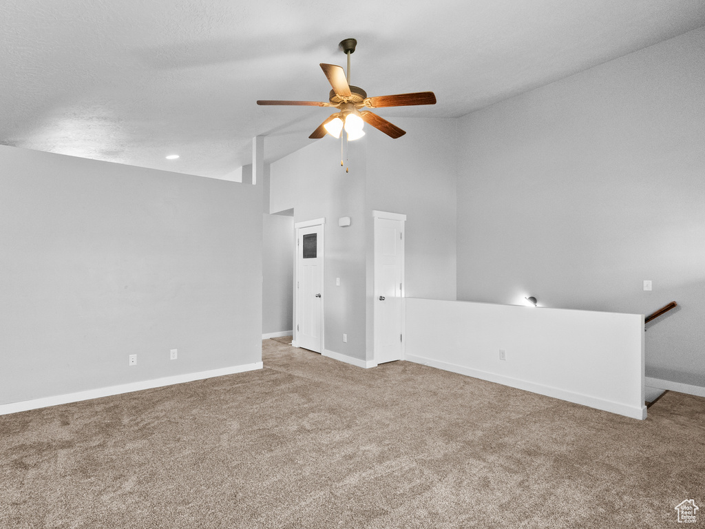 Carpeted empty room featuring a ceiling fan and lofted ceiling