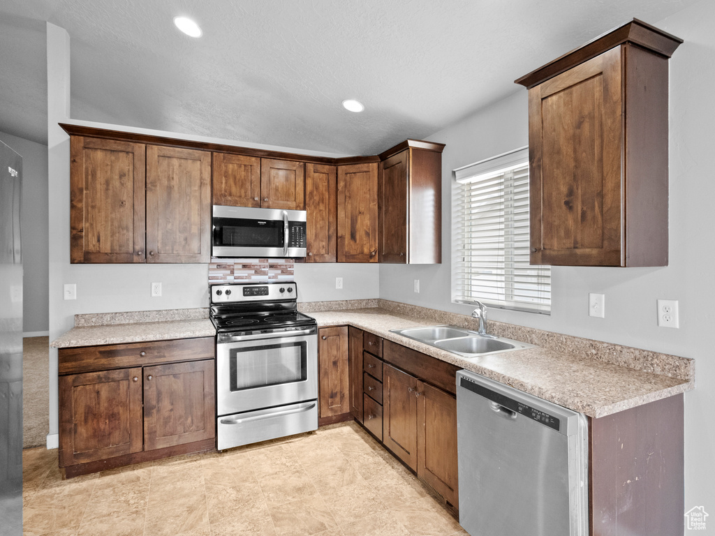 Kitchen with appliances with stainless steel finishes, light countertops, and recessed lighting