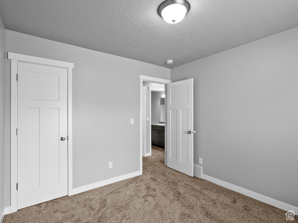 Unfurnished bedroom featuring carpet and a textured ceiling