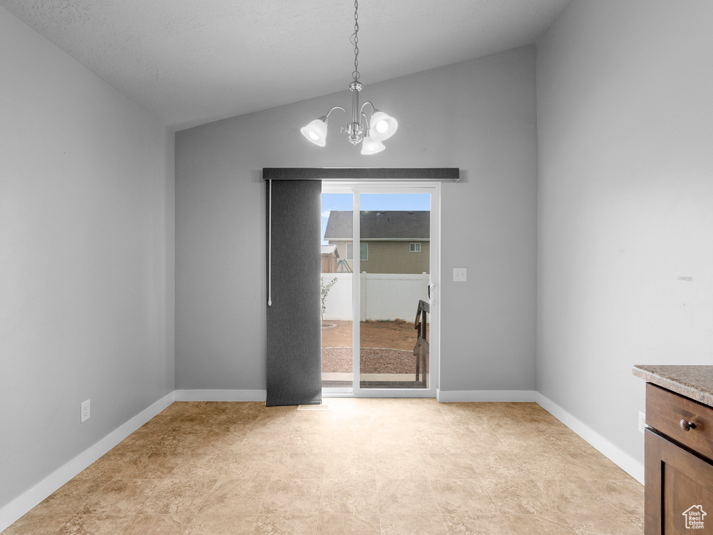 Empty room with a chandelier and lofted ceiling