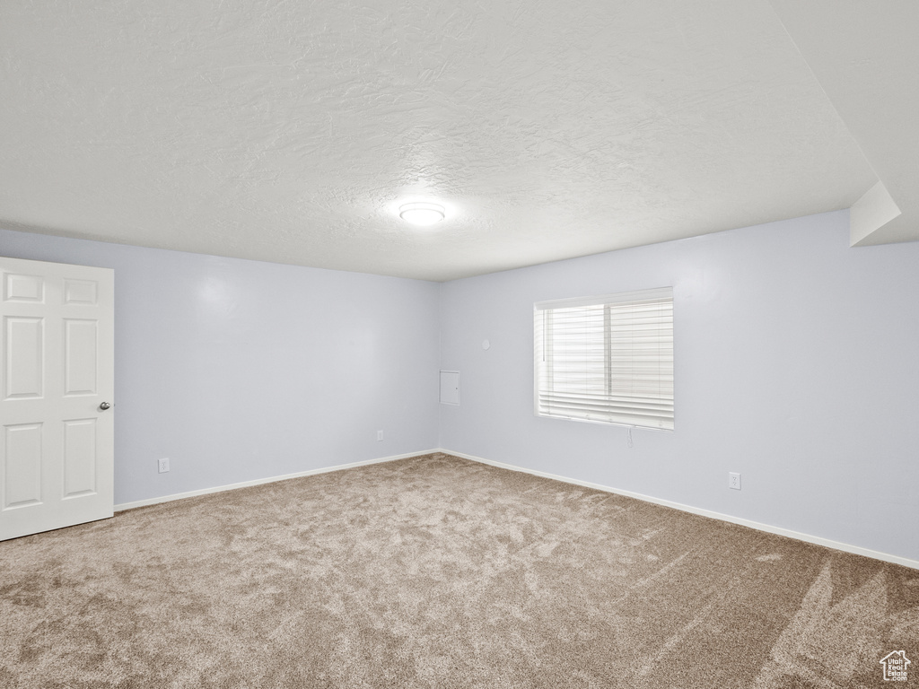 Carpeted empty room with a textured ceiling and baseboards