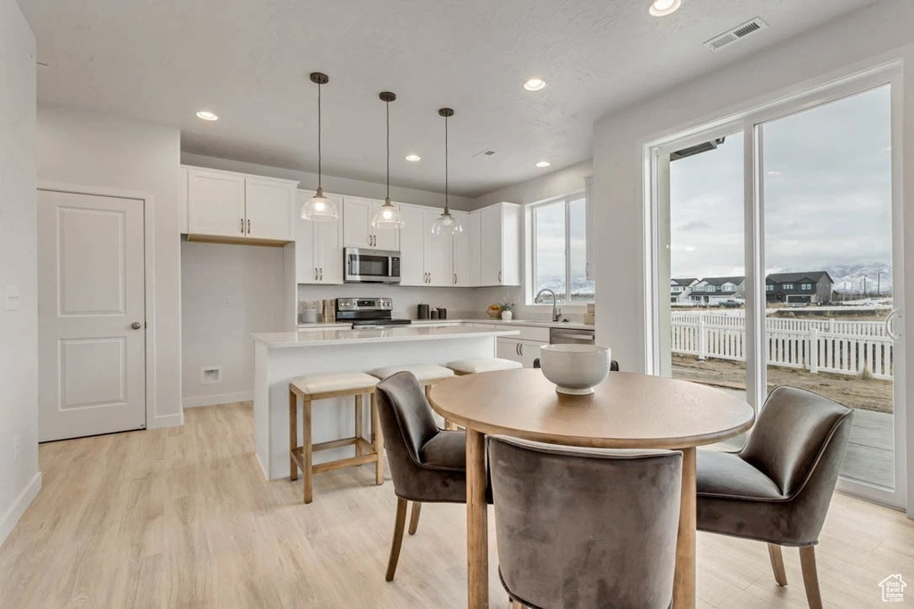 Dining room with light wood finished floors and recessed lighting