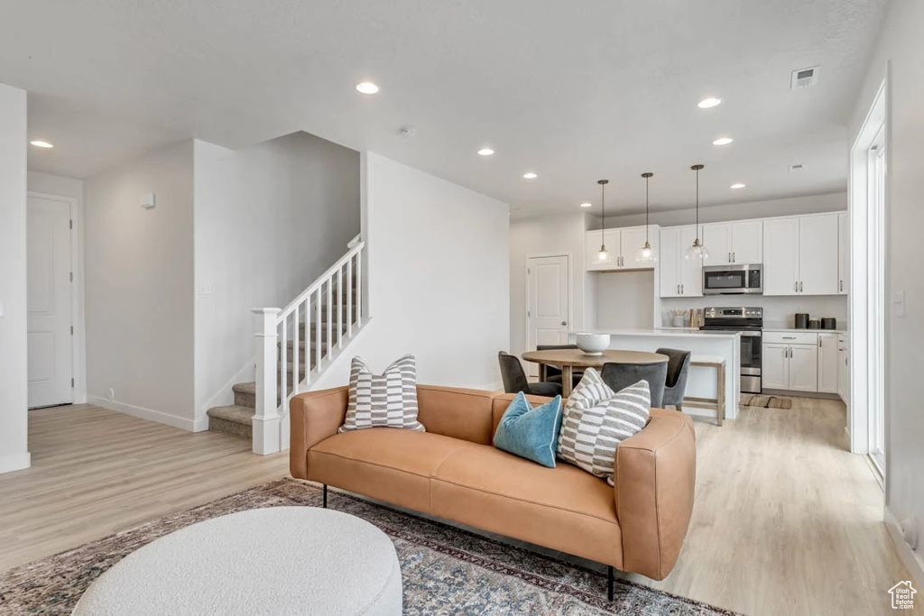 Living room with light wood-type flooring, stairs, and recessed lighting