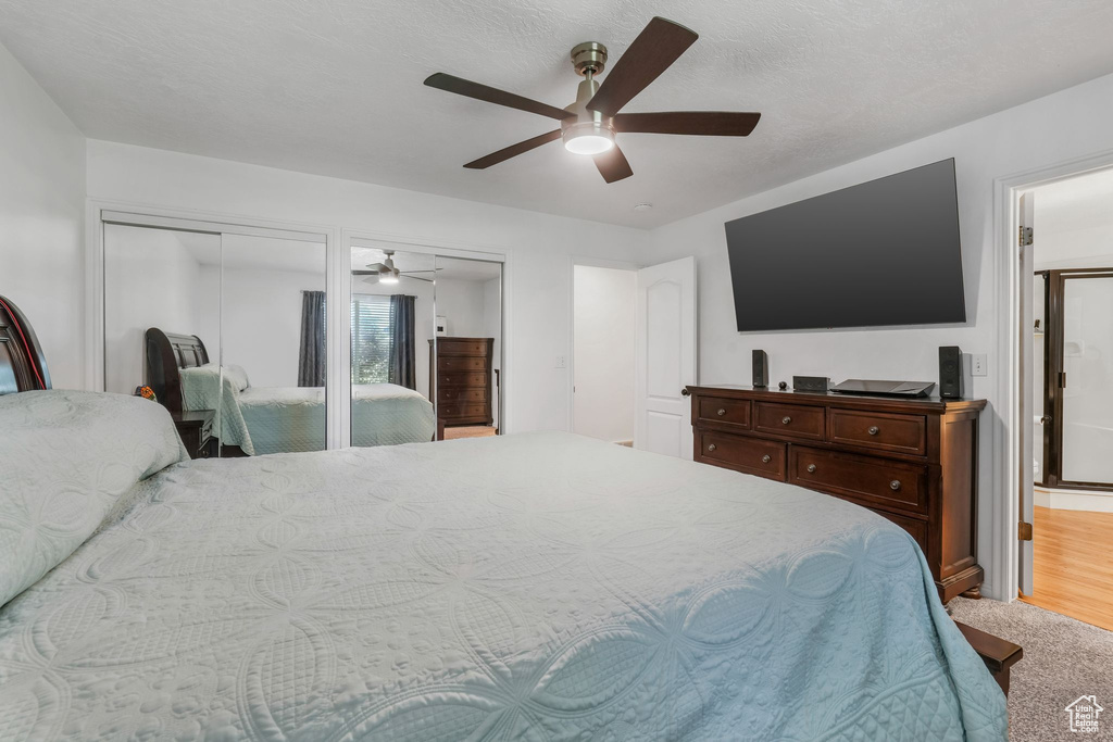 Bedroom with carpet, ceiling fan, multiple closets, and ensuite bath