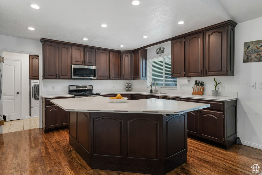 Kitchen featuring appliances with stainless steel finishes, dark brown cabinets, a center island, light countertops, and recessed lighting