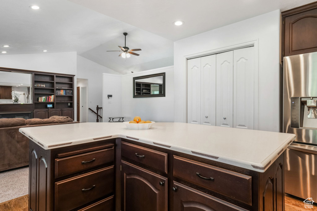 Kitchen featuring stainless steel fridge with ice dispenser, light countertops, a ceiling fan, light wood-type flooring, and vaulted ceiling