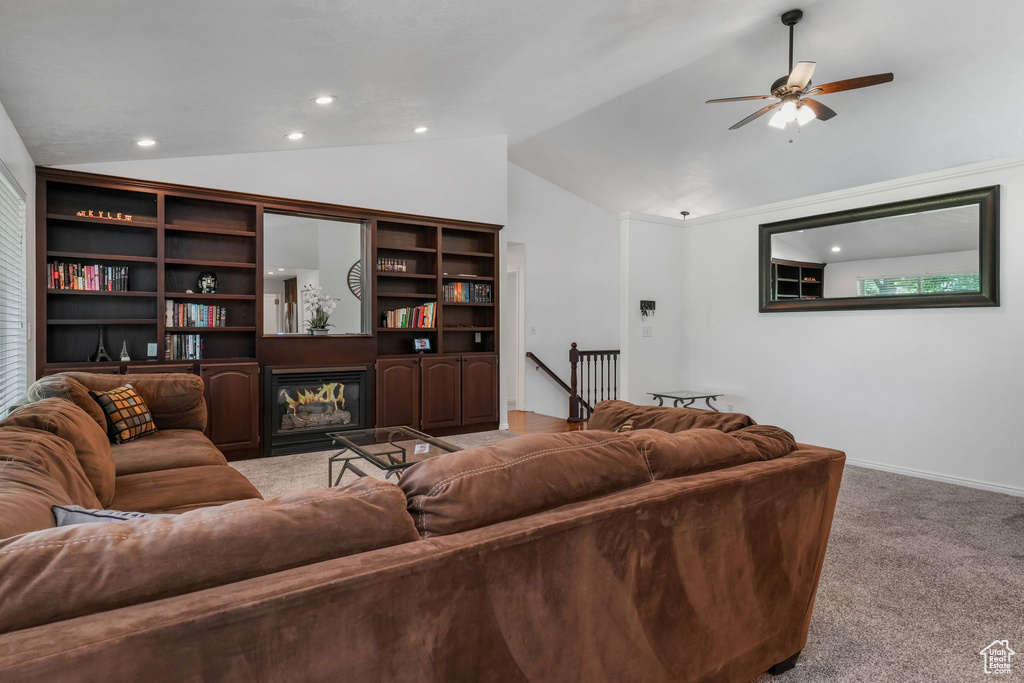 Living room with vaulted ceiling, light colored carpet, a ceiling fan, recessed lighting, and a glass covered fireplace