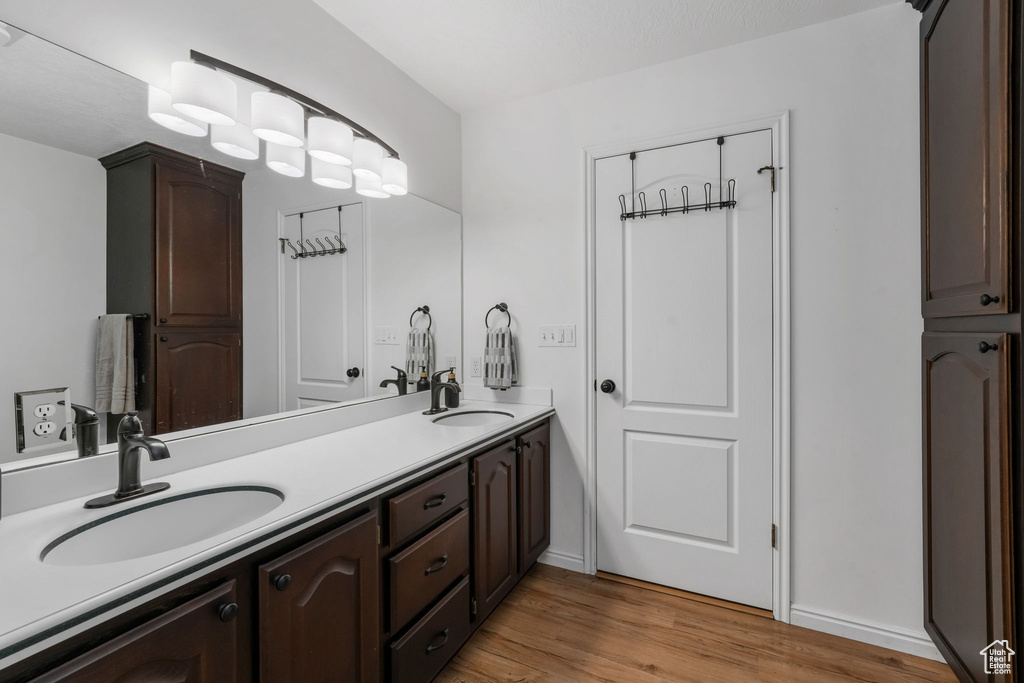 Full bathroom with double vanity and wood finished floors