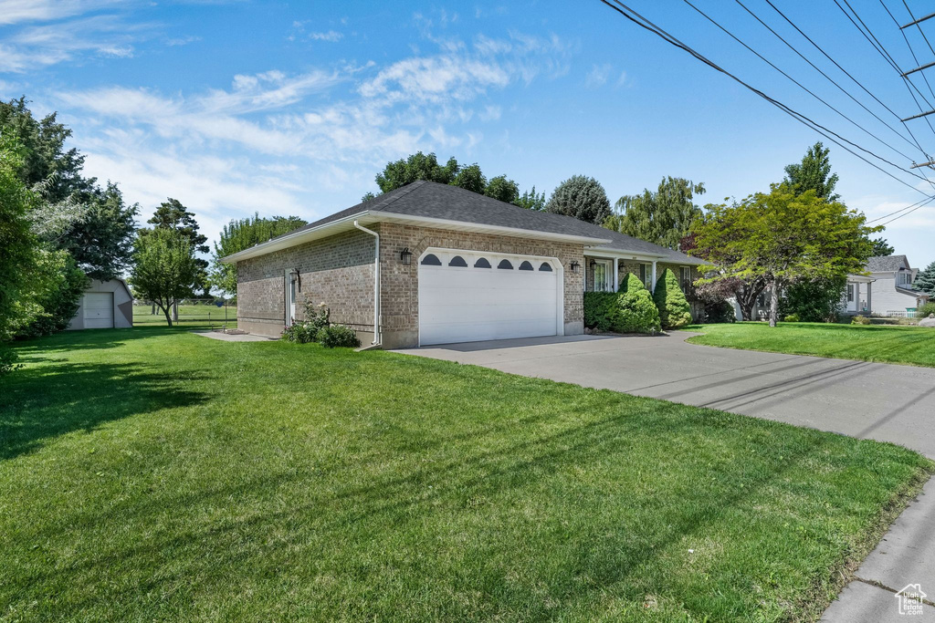Ranch-style house with a front lawn, an attached garage, driveway, and brick siding