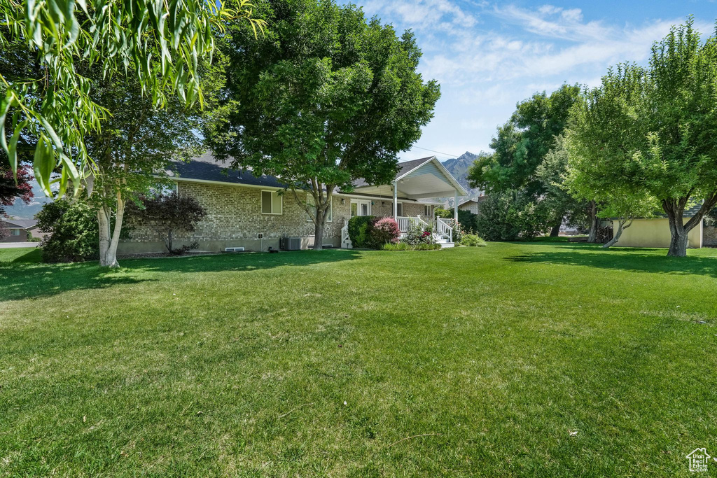 View of grassy yard featuring covered porch